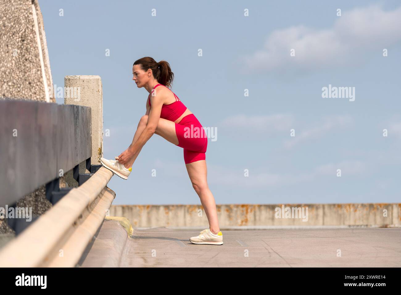 Woman runner tying shoelaces preparing to go running and jogging outdoors, urban fitness. Stock Photo