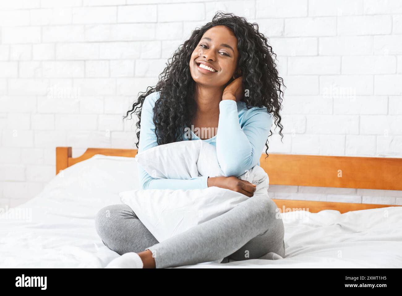 Portrait of pretty charming young woman sitting on bed Stock Photo - Alamy