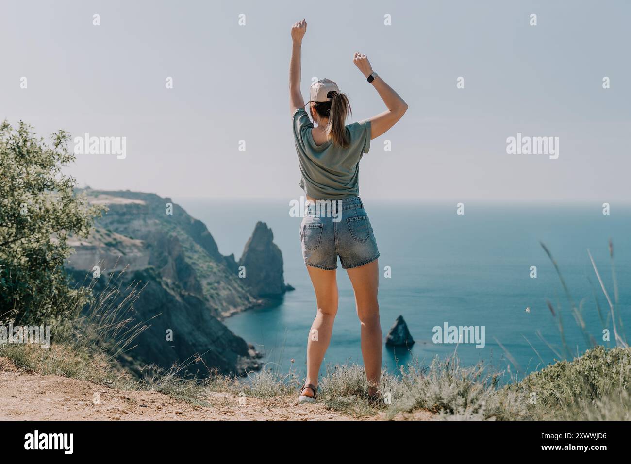 Woman Celebrating on a Clifftop with Ocean View Stock Photo