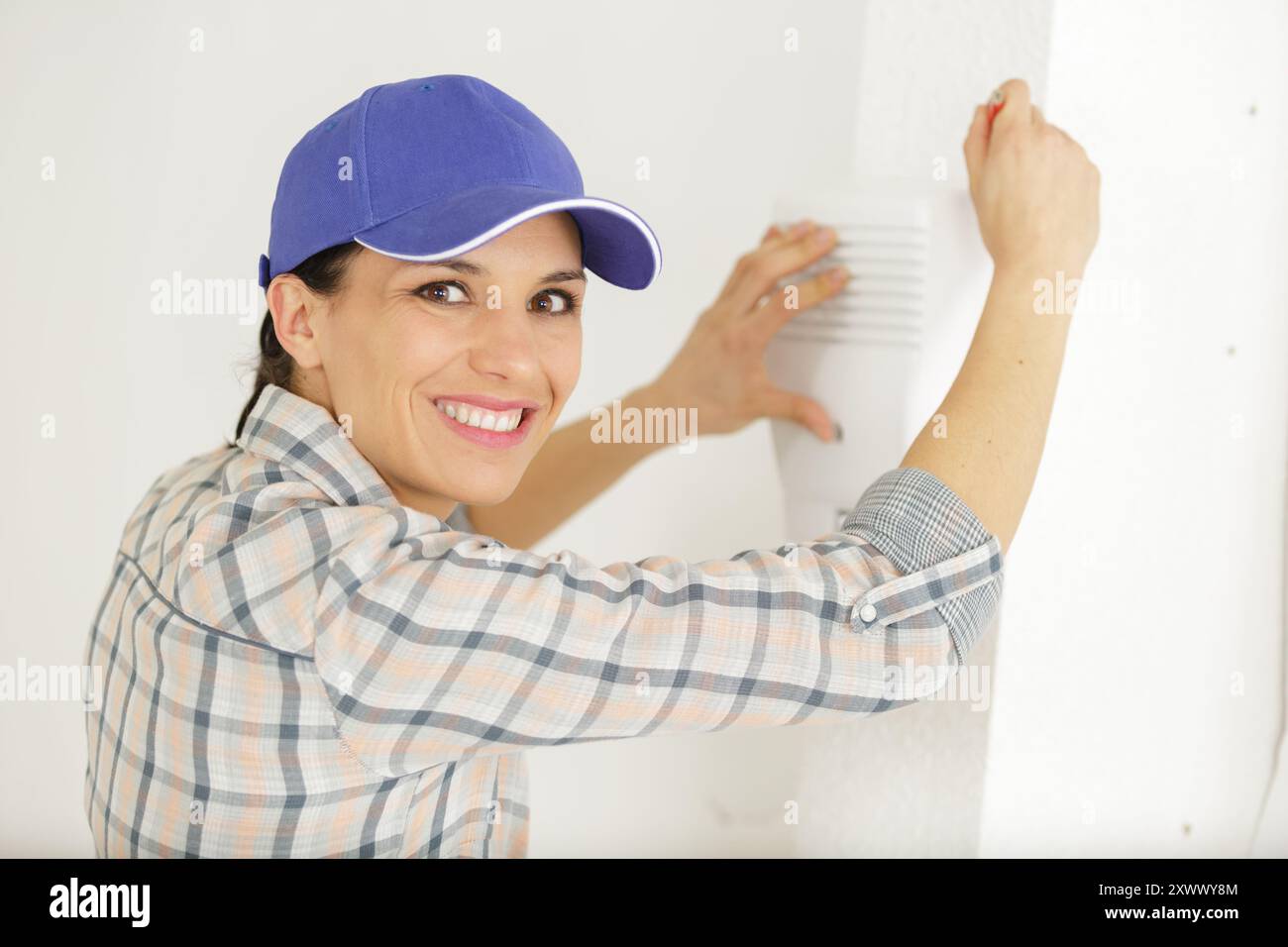 female technician installing security system near door wall Stock Photo