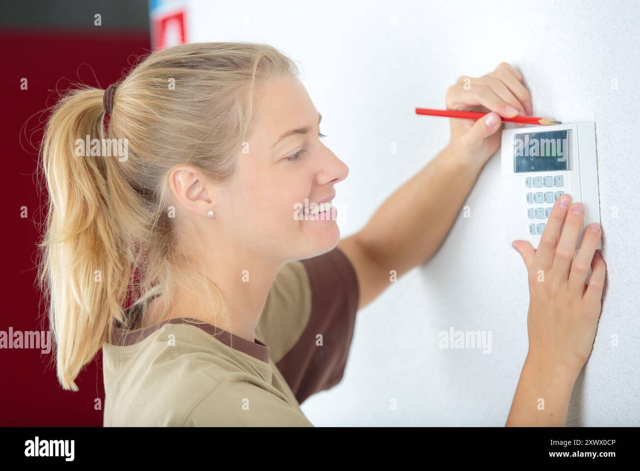 happy female technician installing security system Stock Photo
