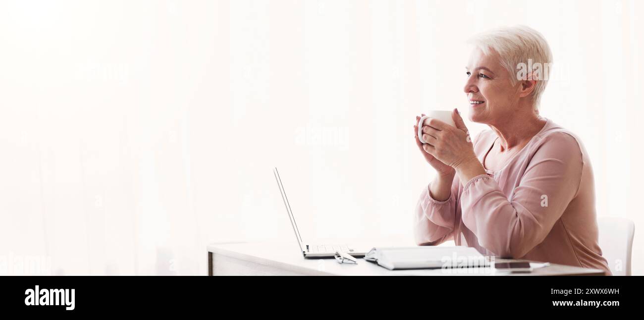 Peaceful old lady having coffee break during working day Stock Photo