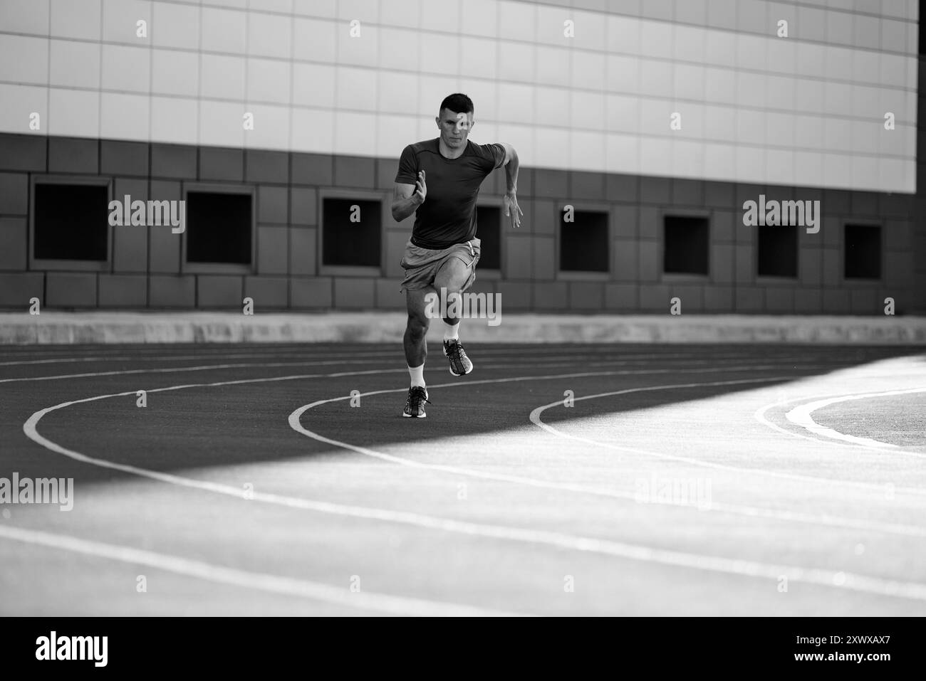 Black and white filter. Young athletic m,an, sprinter picks up speed ...