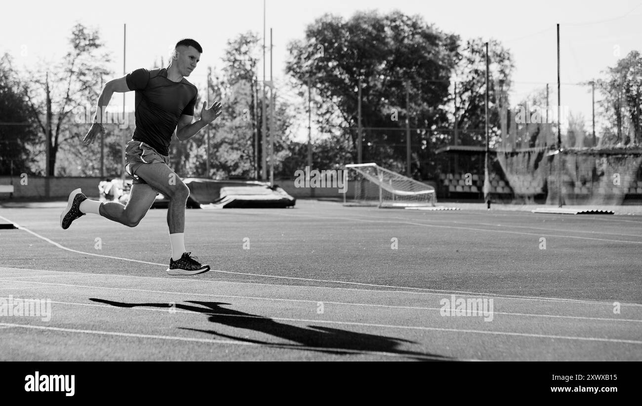 Monochrome photo. Determined athlete powers through curve on track, his ...