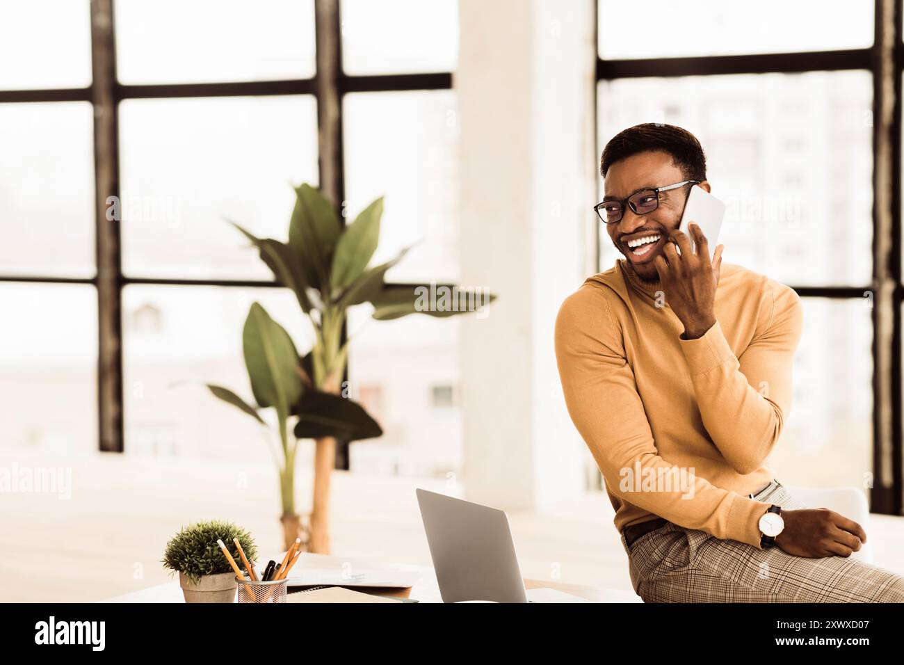 Black guy talking on phone sitting on the table Stock Photo