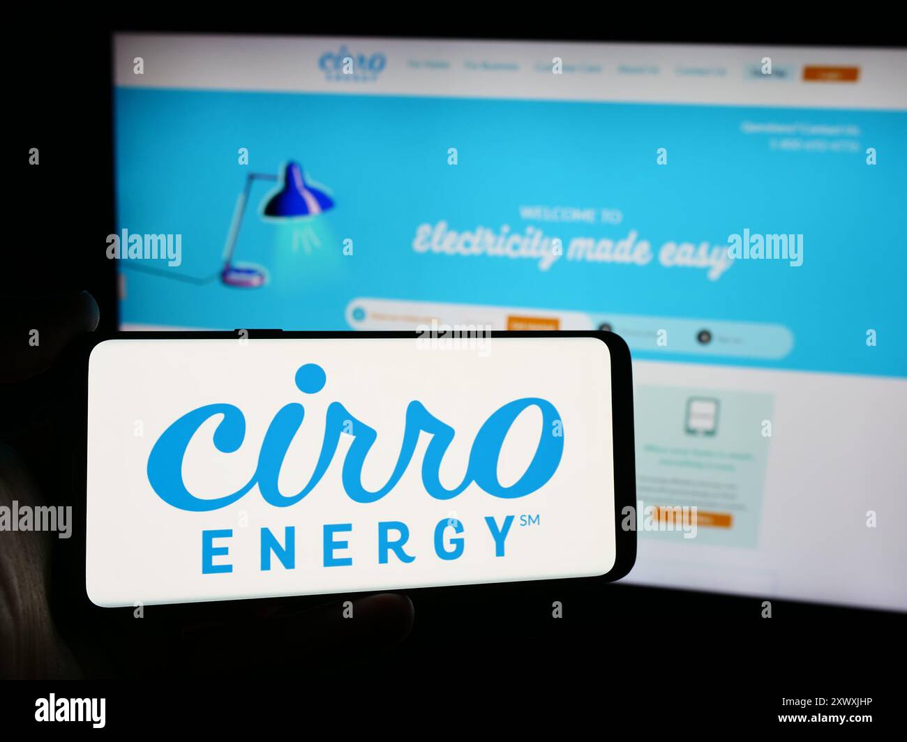 Person holding mobile phone with logo of American electricity 