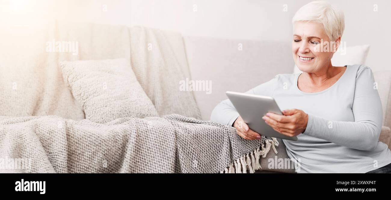 Happy old woman using digital tablet at home Stock Photo