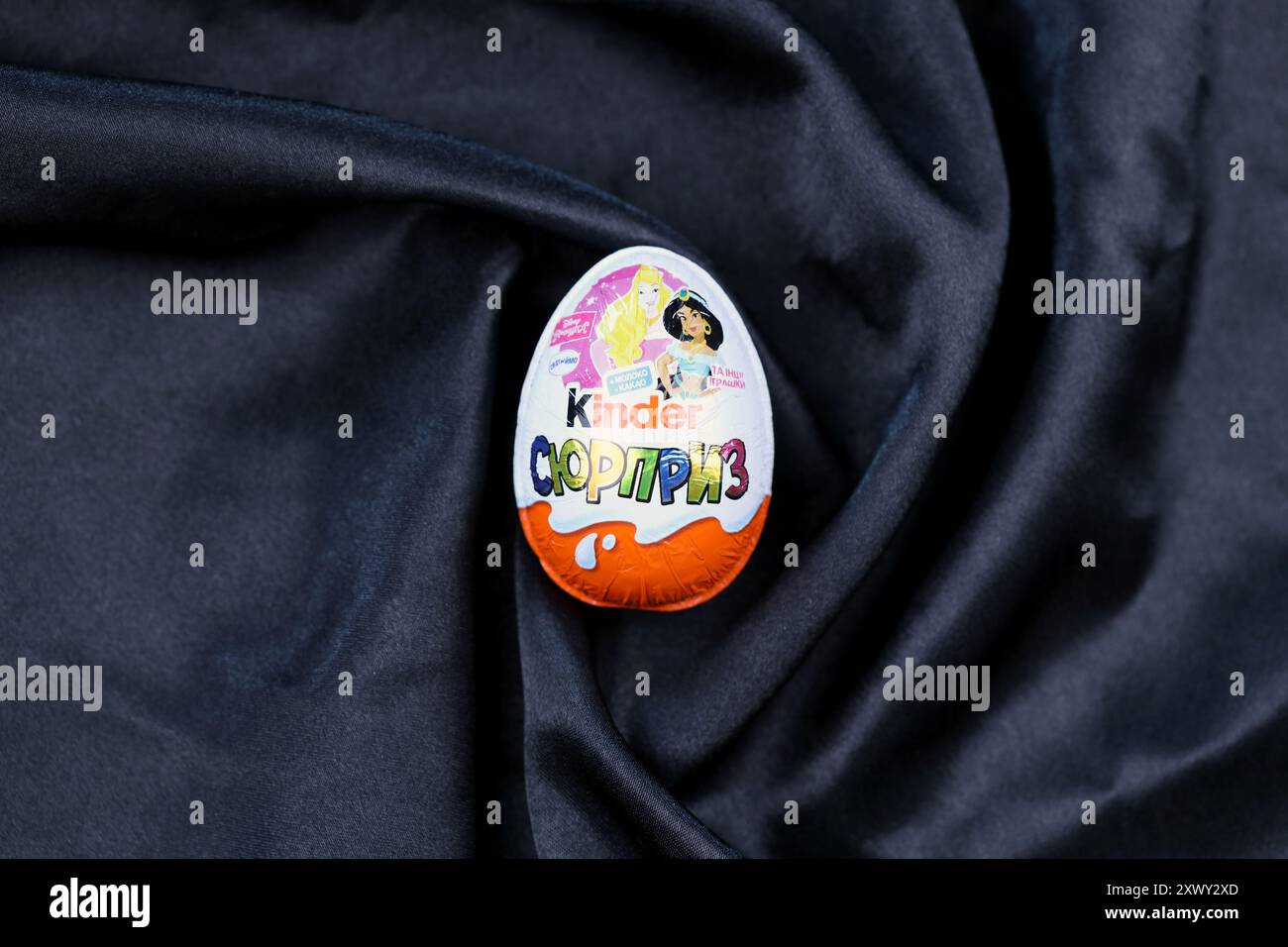 KYIV, UKRAINE - AUGUST 17, 2024 Kinder egg chocolate product with foil wrapping from famous manufacturer close up Stock Photo