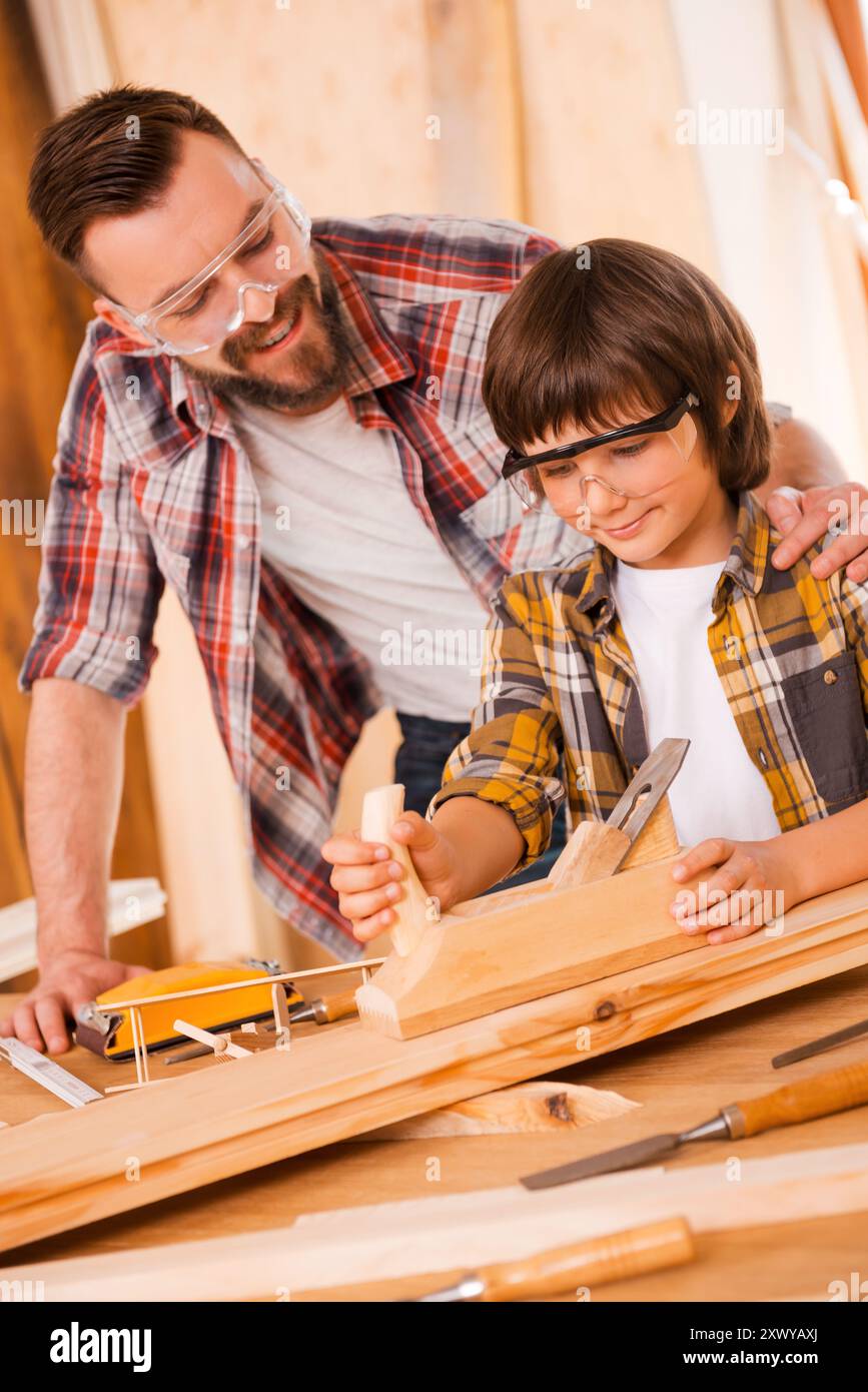 Teaching his son all about carpentry. Happy young male carpenter ...