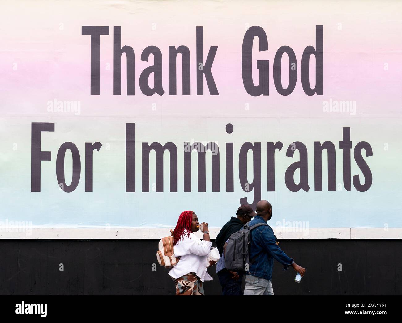 Pedestrians walk past a billboard which reads thank god for