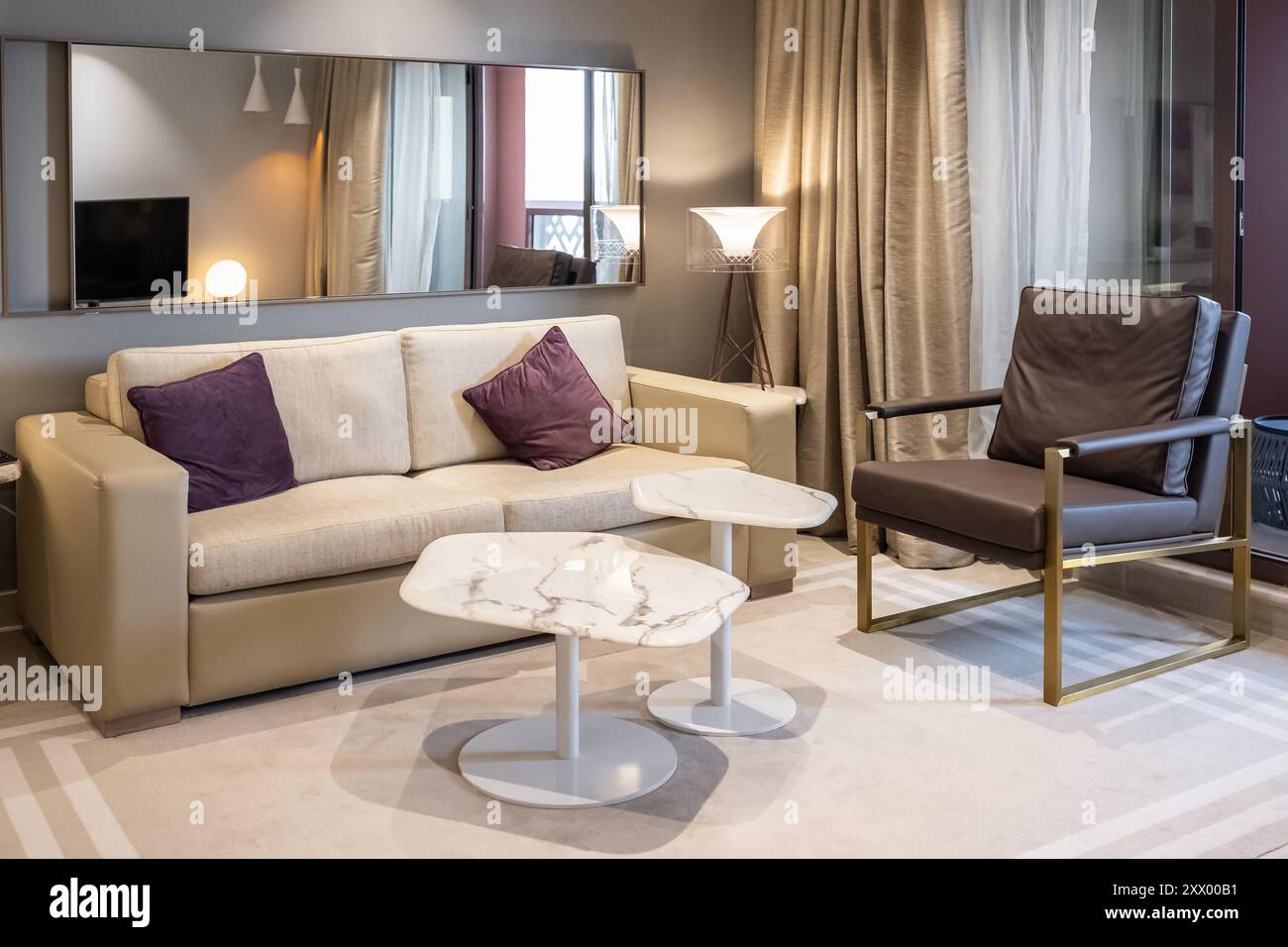 Modern design home interior of living room. Interior of living room with sofa, armchair, tables and glowing lamps in evening. Stylish home decor. Inte Stock Photo