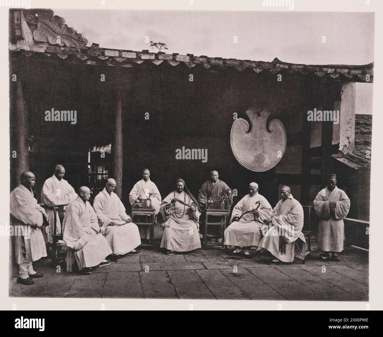 Vintage photo of the abbot and monks of Kushan monastery (Yongquan Monastery). Drum Mountain, Fuzhou, China. Illustrations of Qing China, 1875 It is interesting to note how closely the dress of the Buddhist monk resembles the monastic garb of ancient Europe. In both we see a robe long, simple, and ample, falling loosely to the feet; and both carry a cowl for the protection of the head in cold weather, as well as a rosary to aid the wearer in keeping his debtor and creditor account of good and bad thoughts, words, and works. This account the Buddhist devotee must privately balance during his ho Stock Photo
