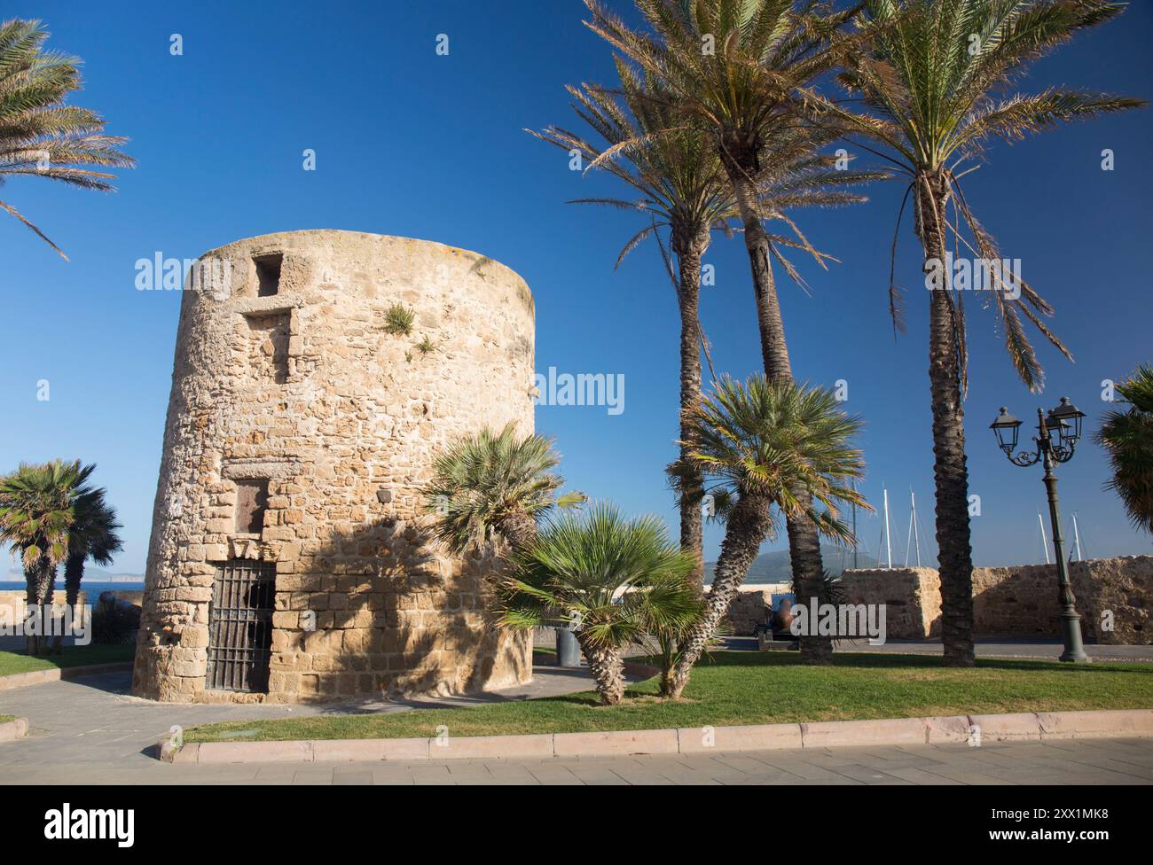 The palm-fringed Torre della Polveriera, a historic stone watchtower in Piazza della Juharia atop the Old Town walls, Alghero, Sassari, Sardinia Stock Photo