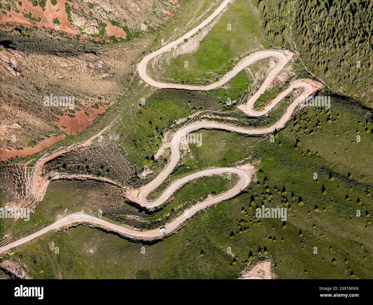 Aerial view of a winding mountain road curves, Kalmak Ashuu Pass, through lush greenery in Kyrgyzstan, Central Asia, Asia Stock Photo