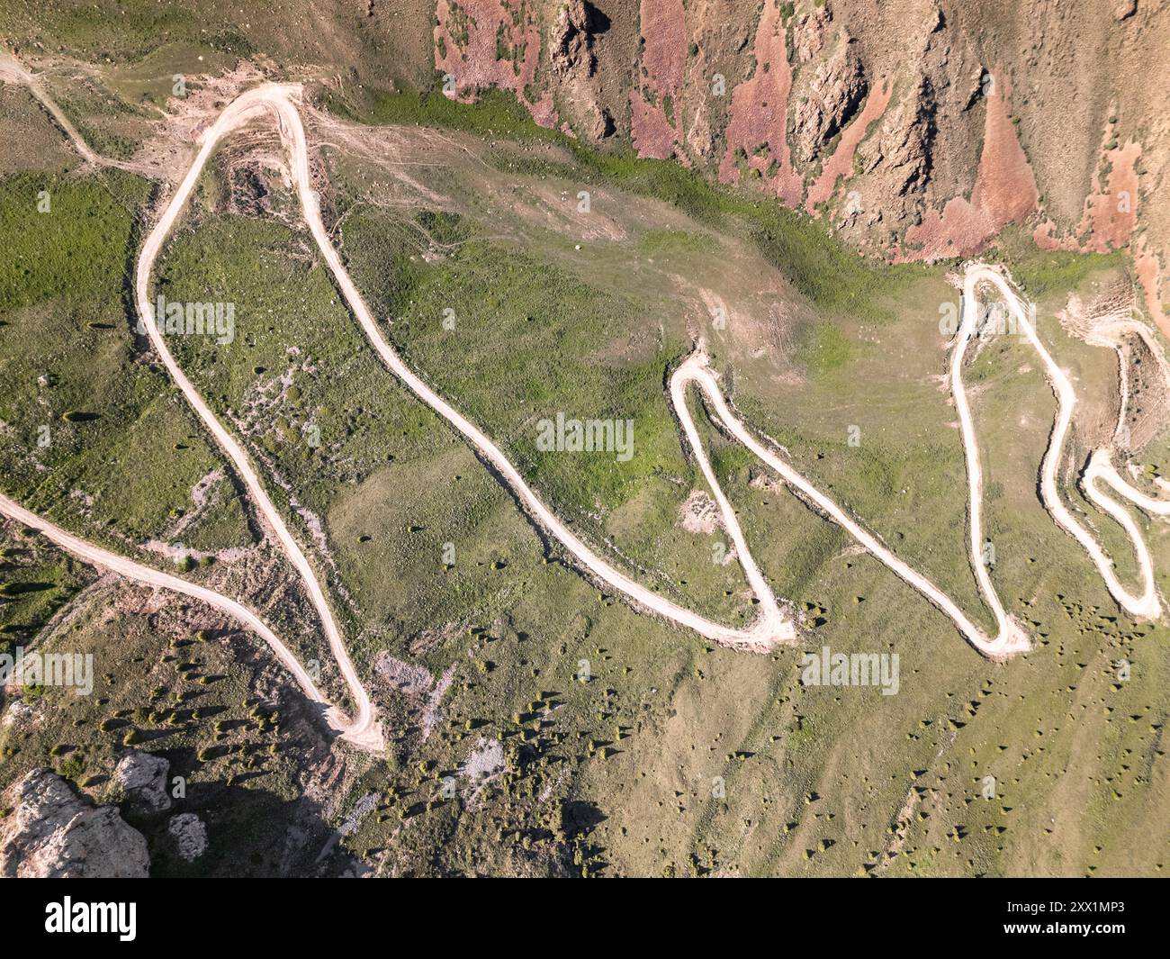 Aerial view of a winding mountain road curves, Kalmak Ashuu Pass, through lush greenery in Kyrgyzstan, Central Asia, Asia Stock Photo