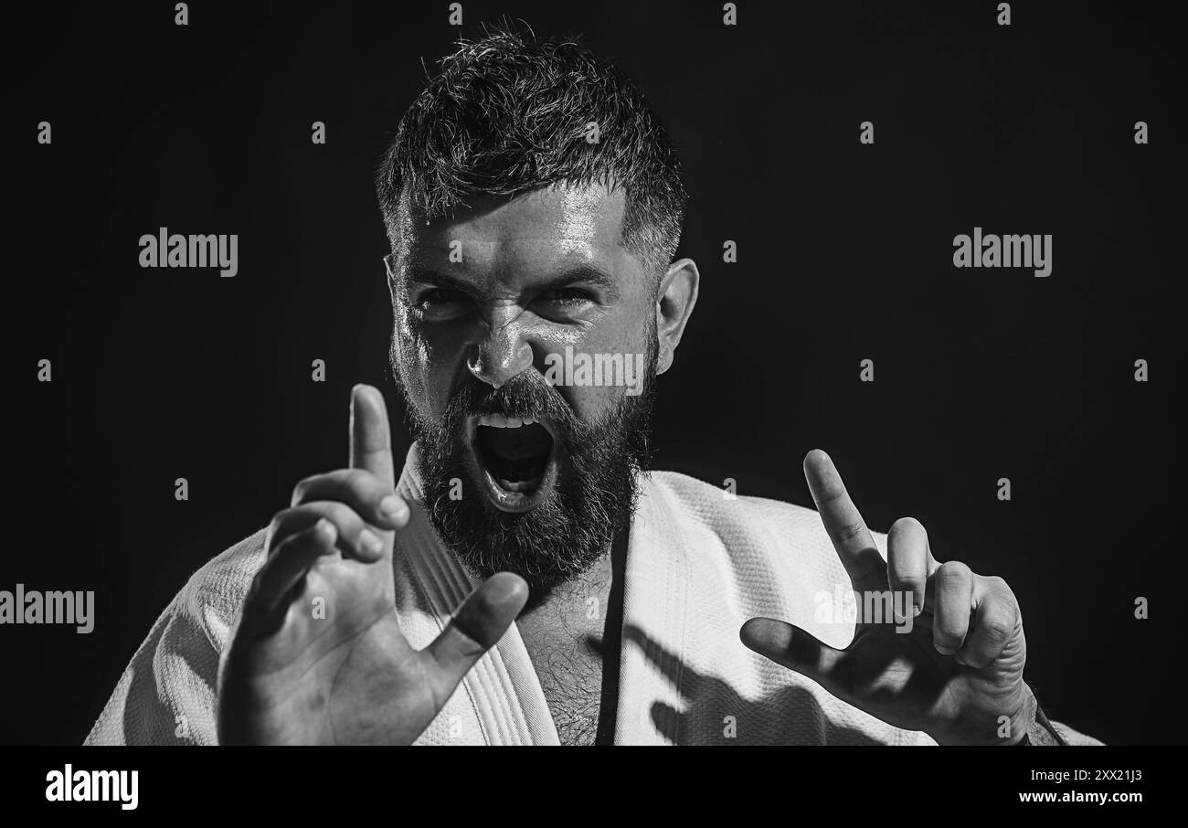 Closeup portrait screaming karate man in fighting position ready for training. Angry karate man in kimono practicing martial arts. Karate fighter Stock Photo