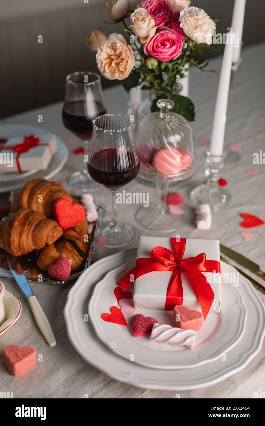 Elegant romantic table setting for two with gifts, croissants, sweet ...