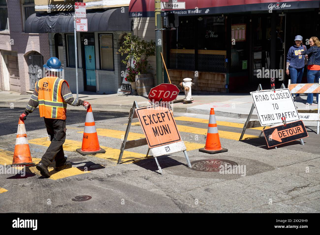 San Francisco, California, United States of America - June 14, 2024: A construction worker in safety clothing places warning cones on a closed road to divert traffic in San Francisco, USA *** Ein Bauarbeiter in Sicherheitskleidung platziert Warnkegel auf einer gesperrten Straße, um den Verkehr umzuleiten in San Francisco, USA Stock Photo