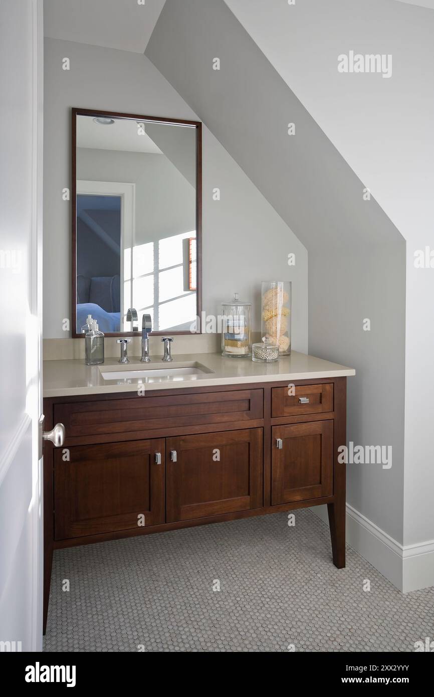 Dark wood vanity set into area under slanted ceiling in second floor bathroom Stock Photo