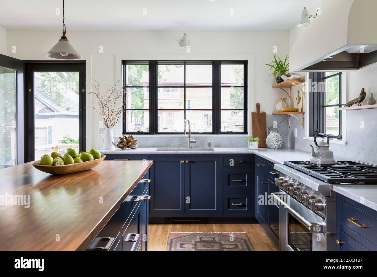 Kitchen with blue cabinets and white marble countertops with view of sink  and windows Stock Photo - Alamy, image size:1300x956