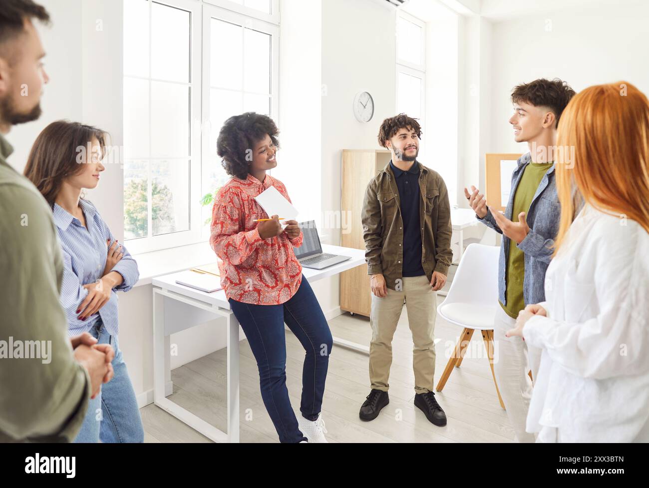 Multiracial group of students or colleagues standing together, talking and sharing work ideas. Stock Photo
