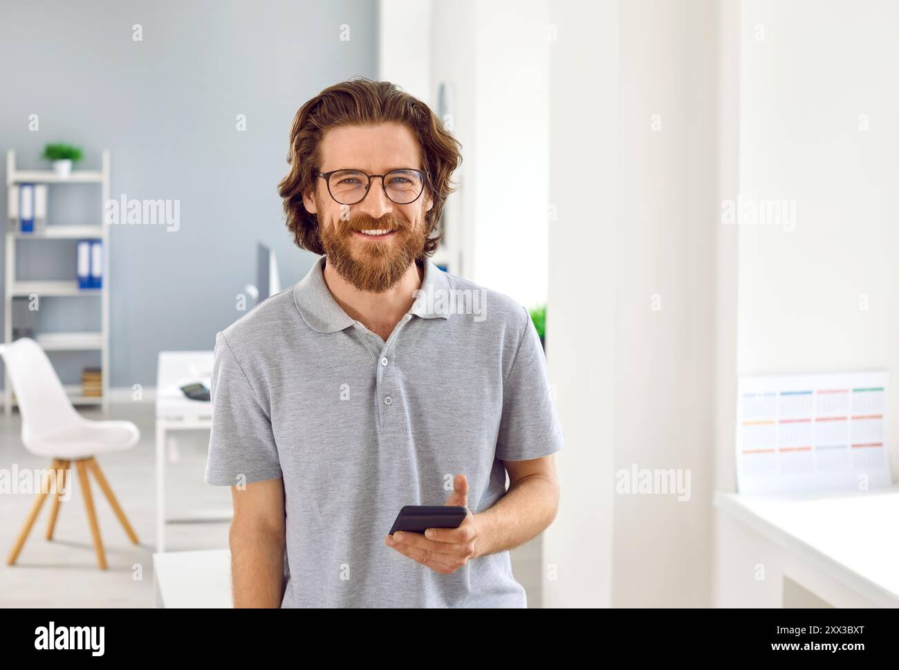Handsome man standing with smartphone smiling at camera Stock Photo