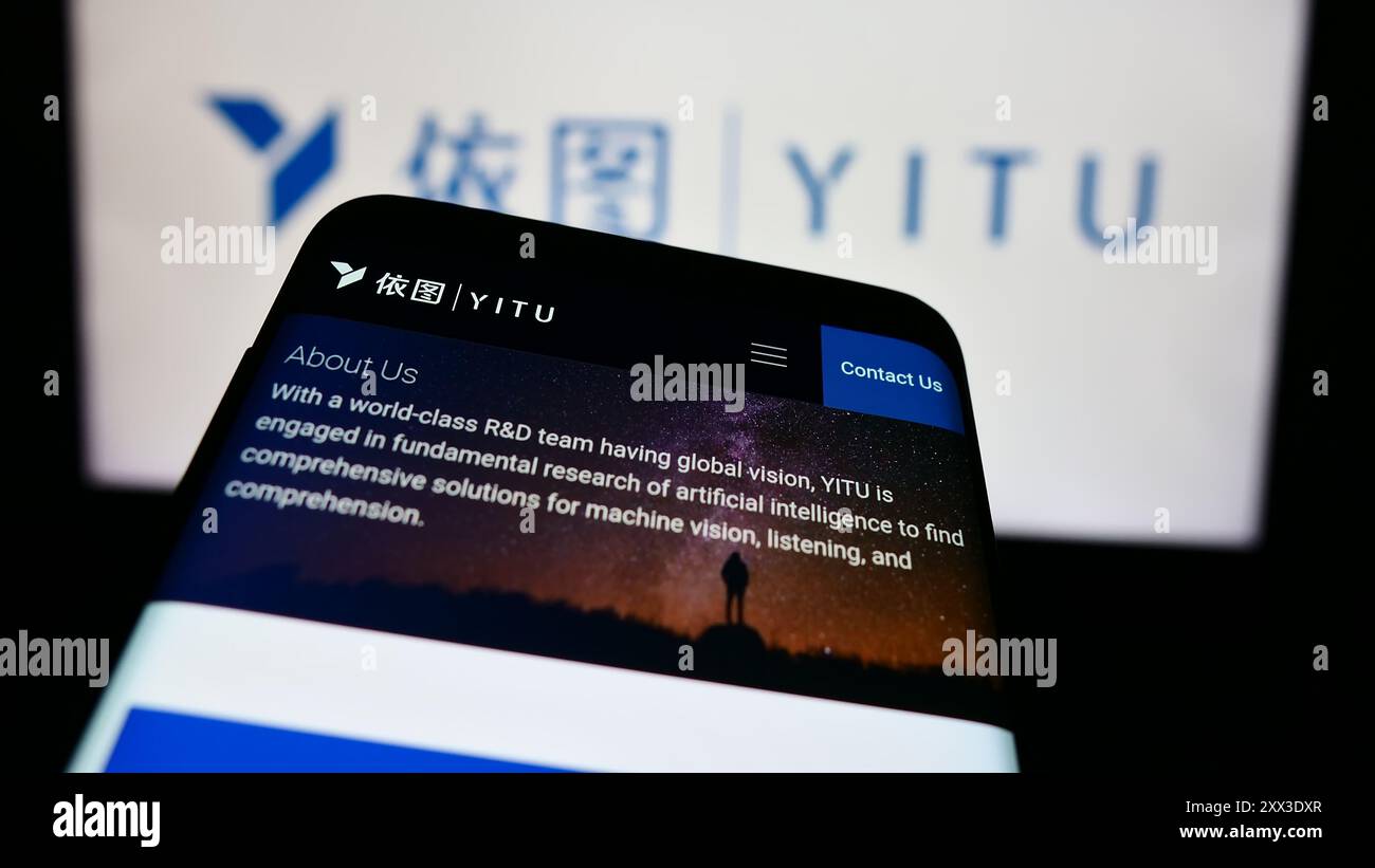 Mobile phone with website of Chinese AI company Shanghai YITU Technology Co. Ltd. in front of business logo. Focus on top-left of phone display. Stock Photo