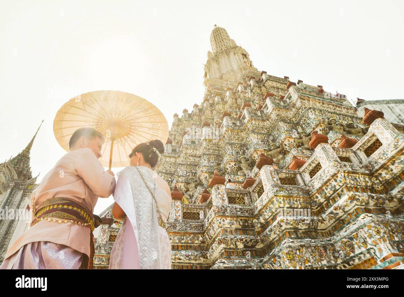 Bangkok, Thailand - 11th february, 2024: young thai couple wear traditional clothes for photo session by Wat Arun beautiful buddhist temple on hot sun Stock Photo