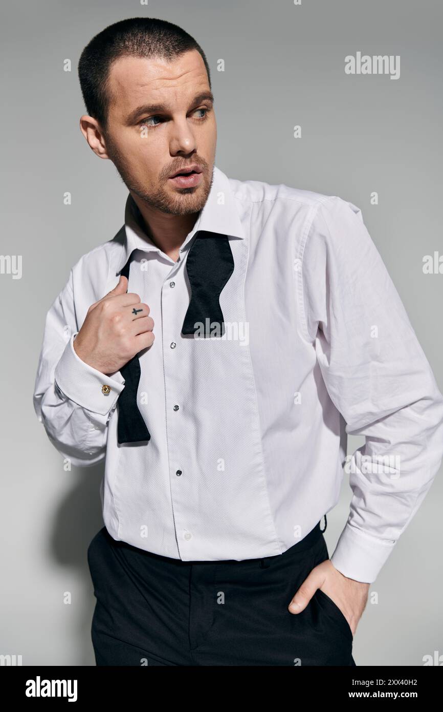 A man in a white shirt and black bow tie adjusts his attire, looking ...