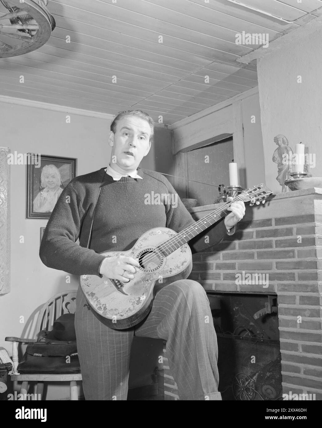 Oslo 19490122Actual 2-1949: From the barn to the parnasset At home with singer Alf Prøysen, who performs with a guitar and a charming look! -'Aktuell' has paid a visit to the author, vice-poet and vice-singer Alf Prøysen. The Prussian held was just entertaining his wife with one of his own shows when 'Aktuell' knocked on the door. It was the cheerful story of what happened on the farm Li when the farmer was in Hamar with slaughter Alf Prøysen had chosen as suitable entertainment for the coffee. The photographer got ready to shoot and captured some changing moods of the visa from the second ver Stock Photo