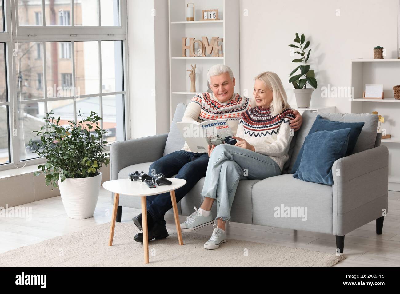 Mature couple reading magazine on sofa at home Stock Photo