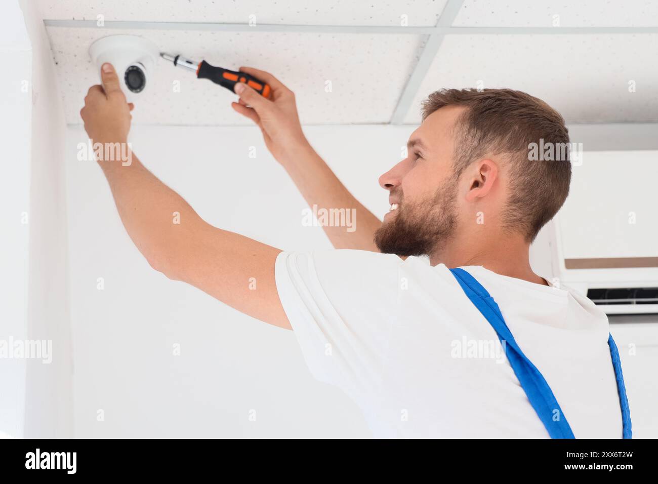 Male worker installing alarm system in room Stock Photo