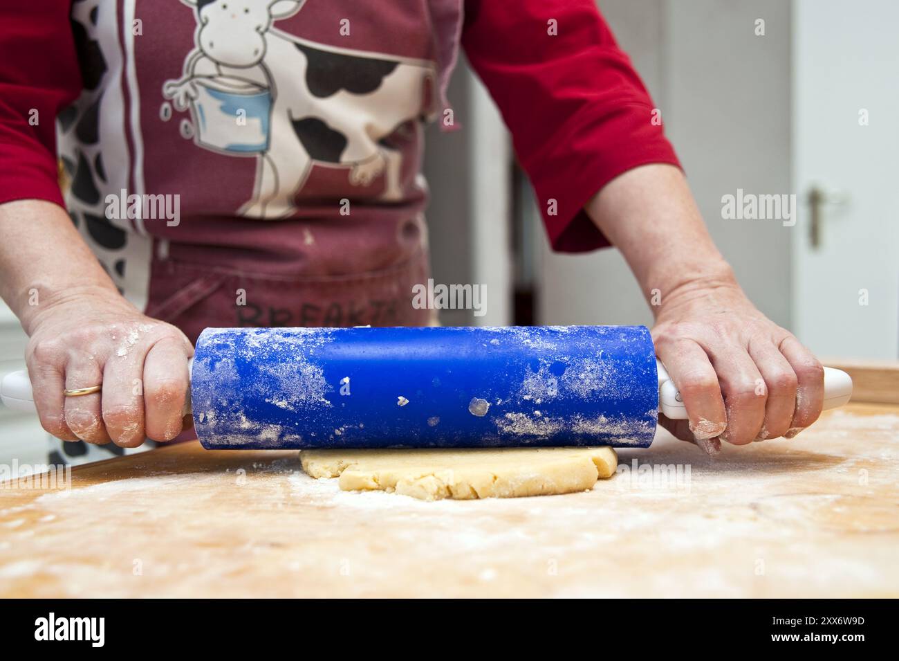 Hands guide rolling pin and roll out dough Stock Photo