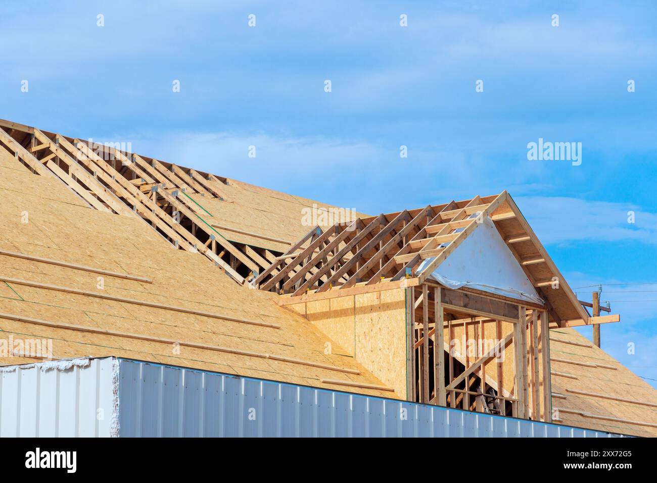 Assembling roof of new house under construction using plywood on wooden trusses Stock Photo