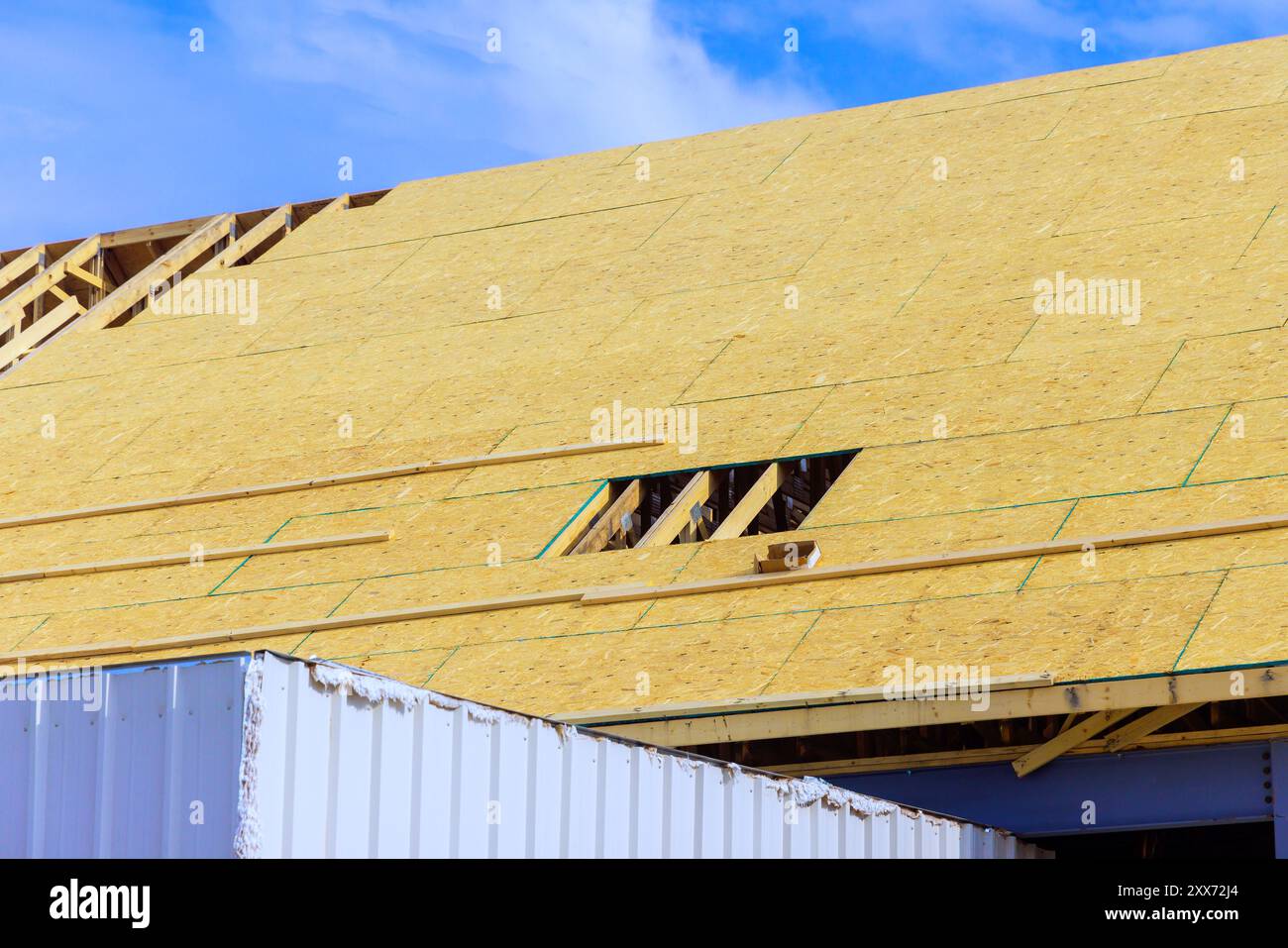 Placing plywood on wooden roofing trusses at assembled roof of an under construction house Stock Photo