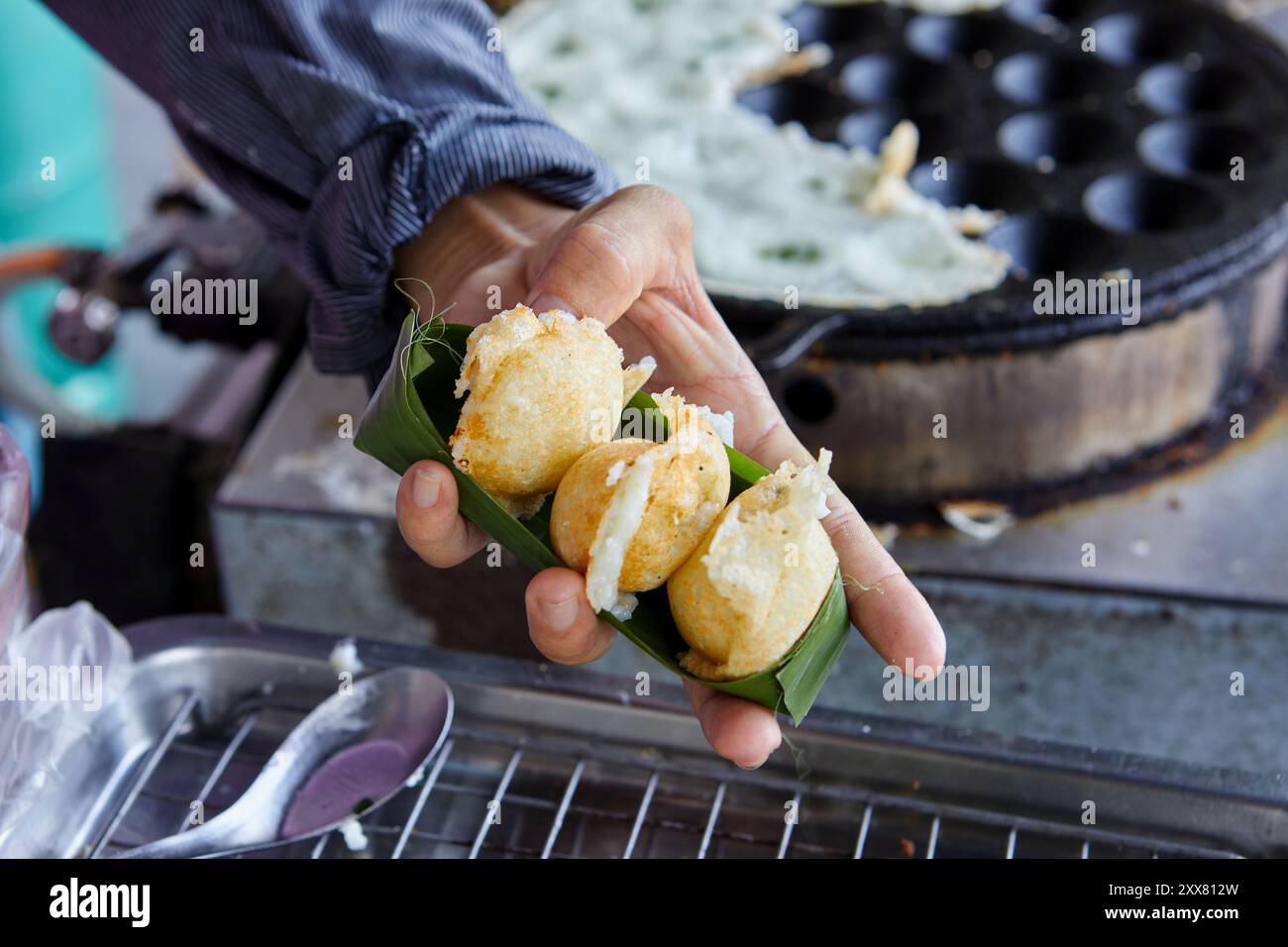 Cropped hand holding Coconut-rice cakes  in banana leaf bowl Stock Photo