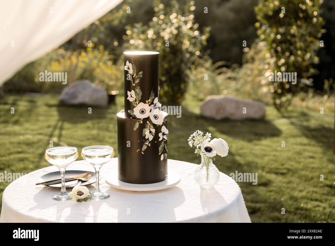 black wedding cake with white flowers on small  round table Stock Photo