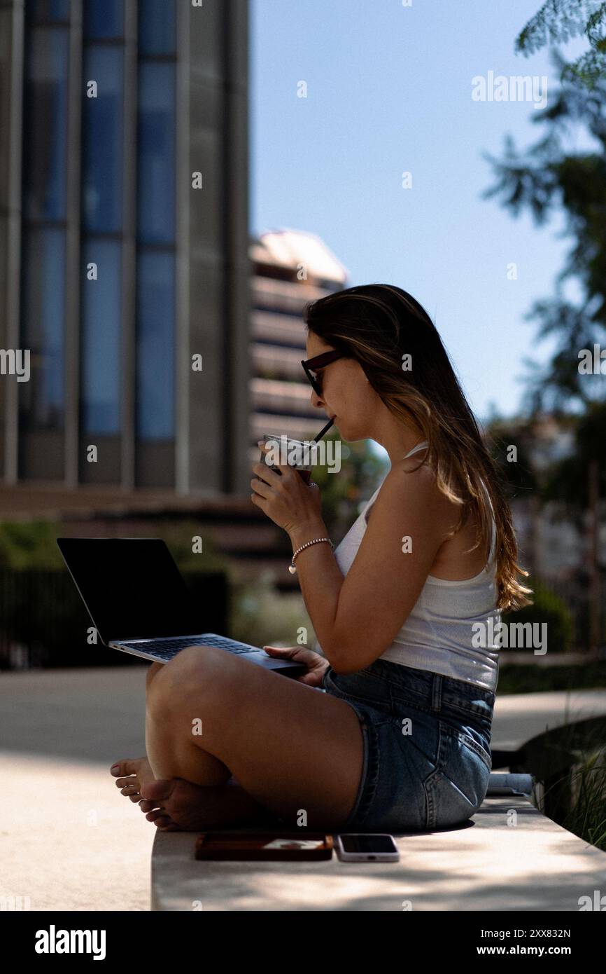 Young woman using laptop on the bench. Stock Photo