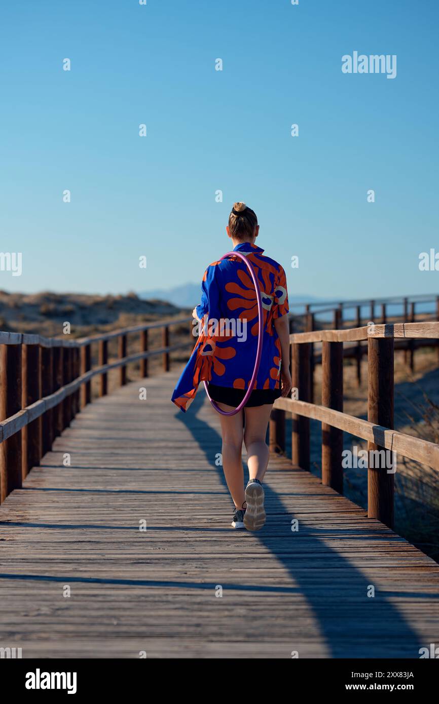 A person walks on a wooden boardwalk wearing a colorful wrap Stock Photo