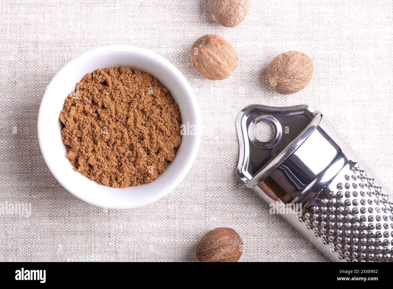 Nutmeg powder, ground nutmeg in a white bowl on linen fabric. Fragrant ...