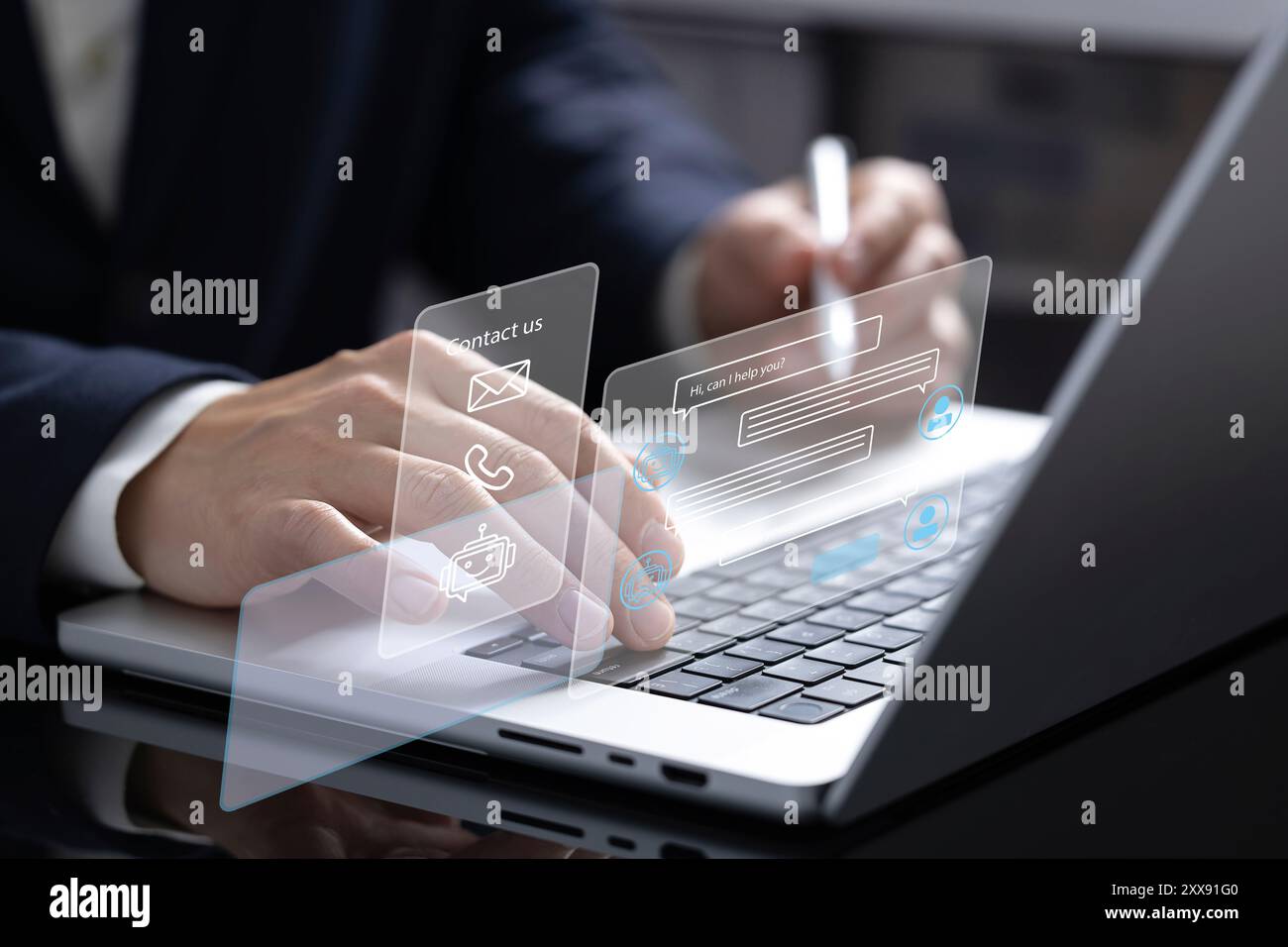 A businessman works on his laptop, interacting with an online customer service chatbot displayed as a hologram. The chatbot assists with prompt and ef Stock Photo