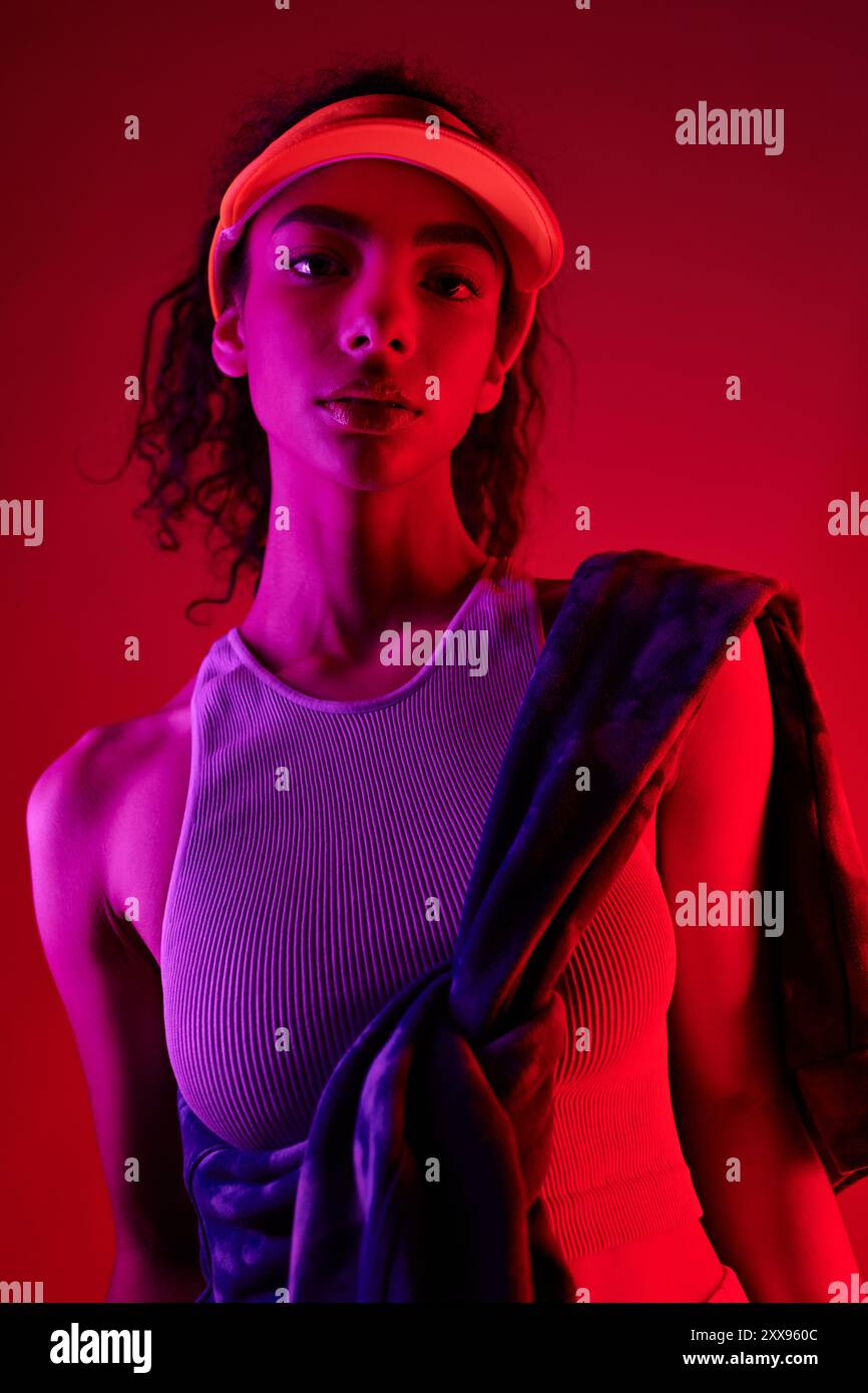 A young woman with dark curly hair poses confidently in a studio ...