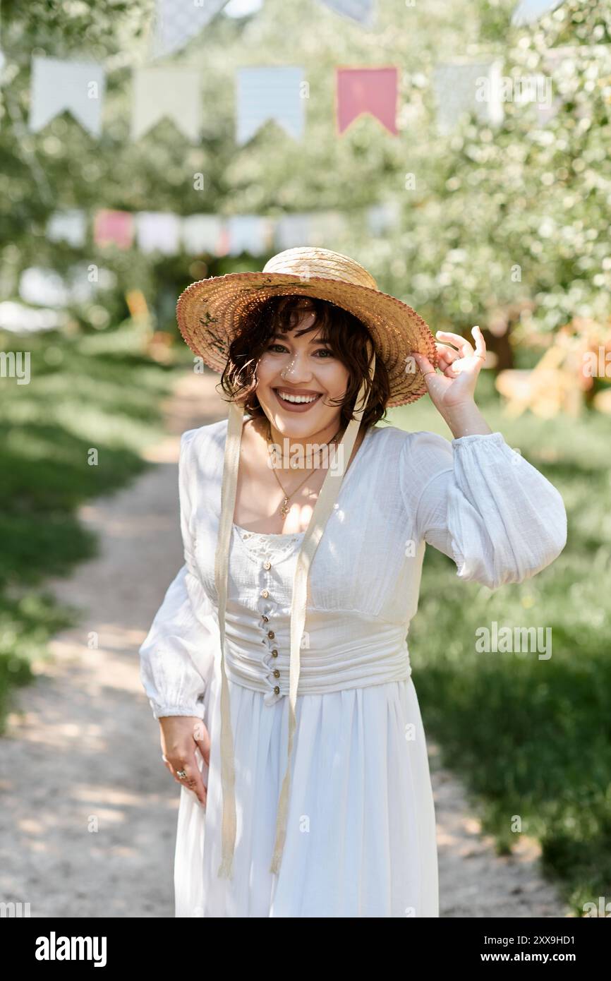 A young woman in a white dress and straw hat smiles as she walks ...