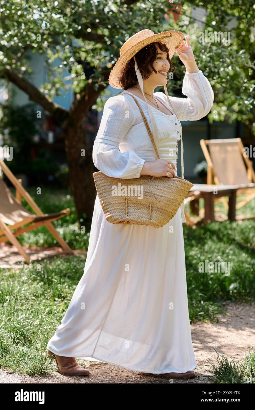 A young woman in a white dress and straw hat walks through a garden ...