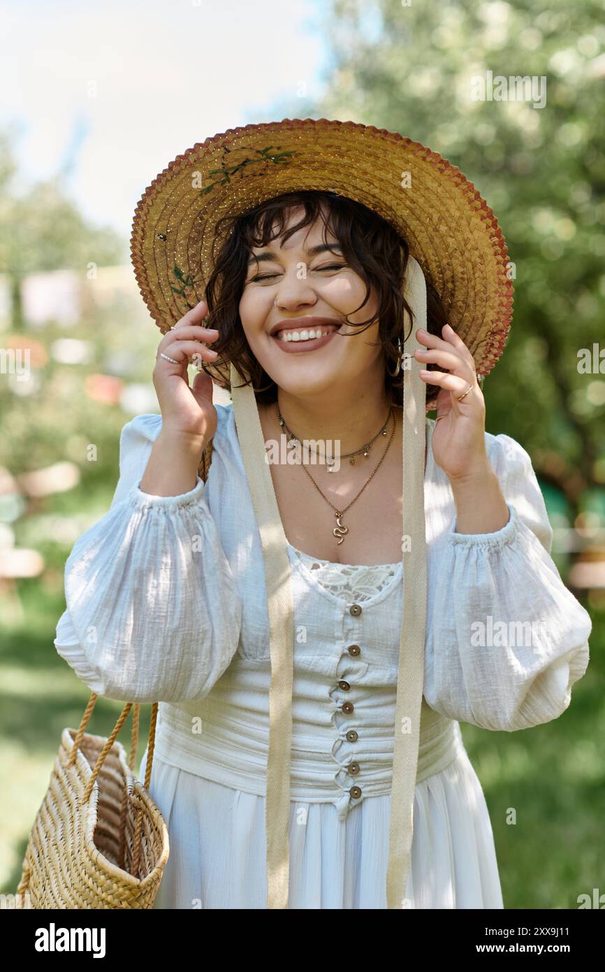 A beautiful brunette woman in a white blouse and straw hat laughs while ...