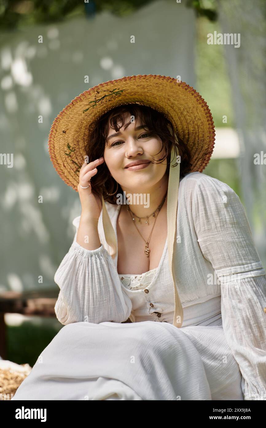 A brunette woman smiles sweetly while wearing a straw hat and a white ...