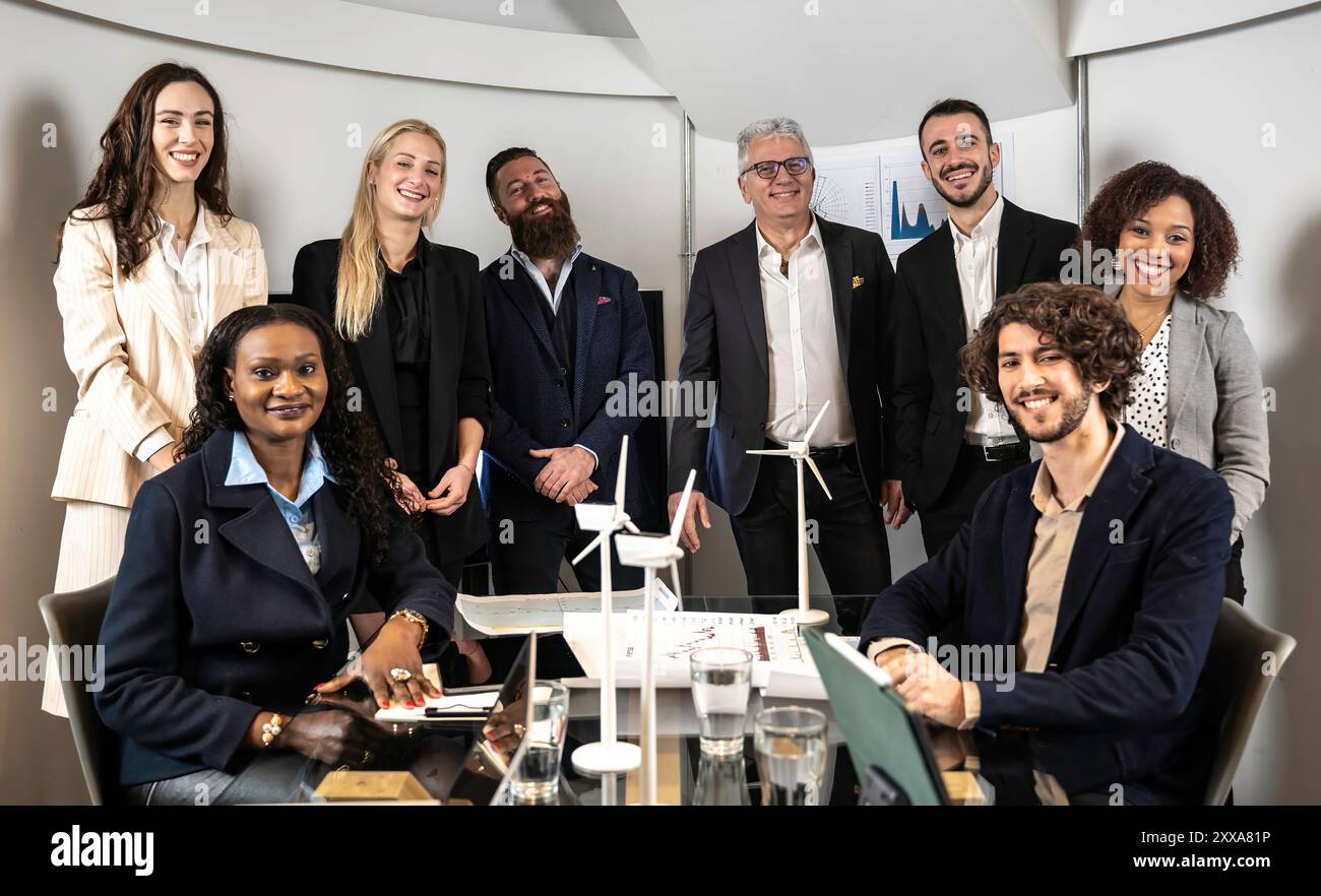 Diverse business team smiling confidently during a meeting focused on renewable energy solutions. Teamwork, sustainability, and corporate success. Stock Photo