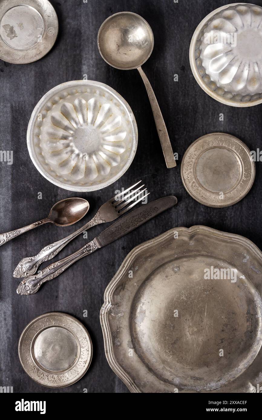 Vintage pewter plates, bowls and cutlery on black chalkboard background ...