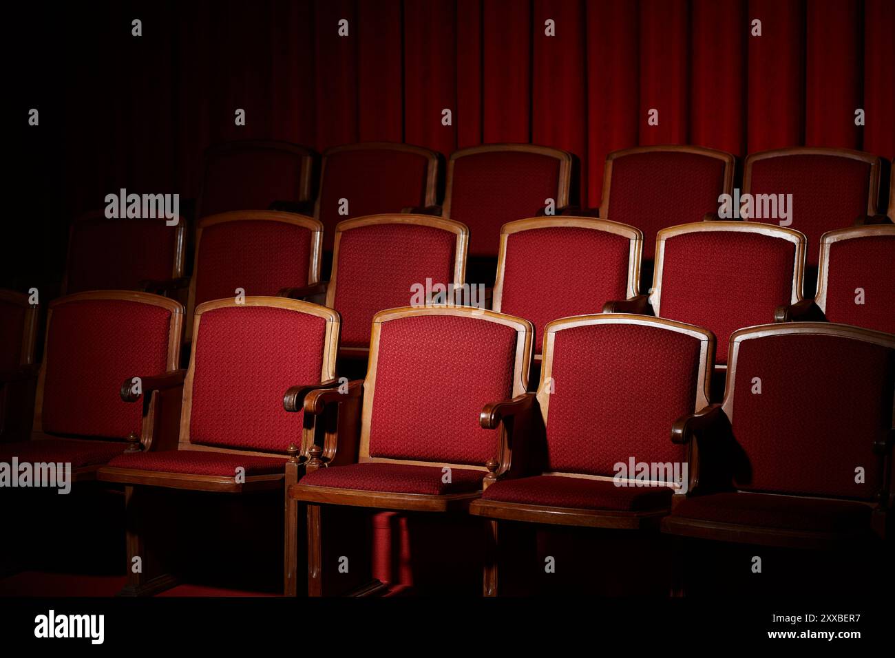 Rows of empty red velvet seats in a darkened movie theater ...