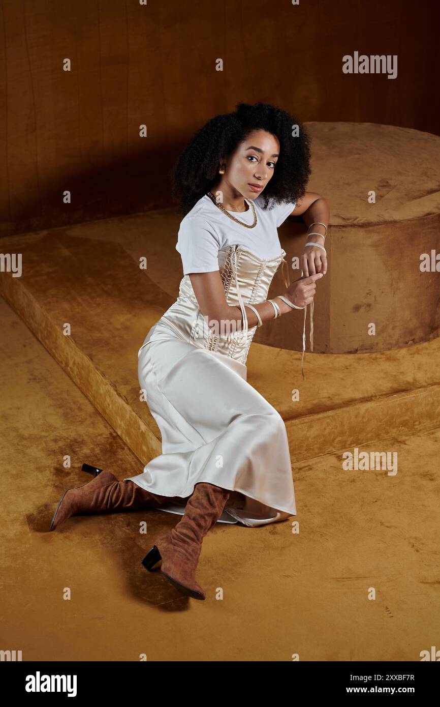 A stylish African American woman in a white outfit poses in a studio ...